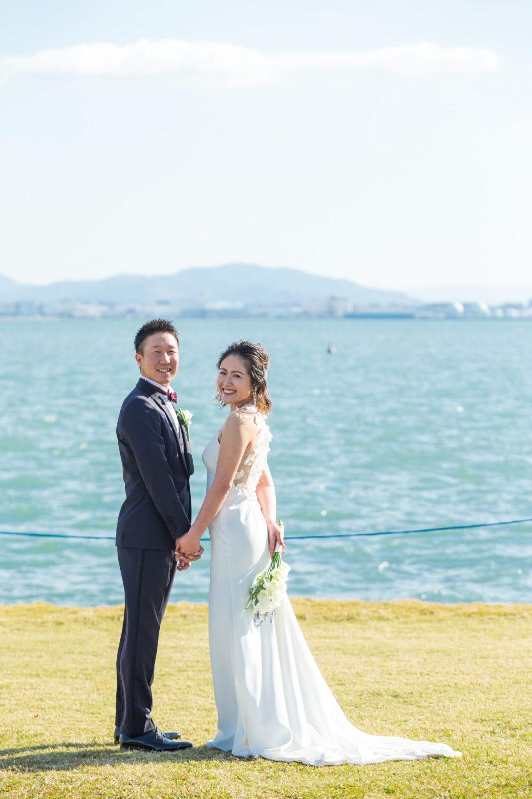 海とウェディングドレスのコントラストが美しい前撮り写真