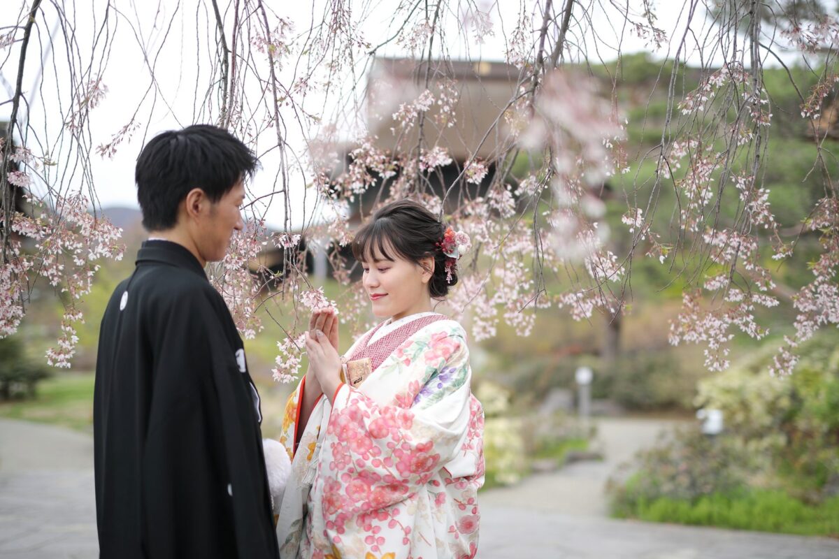 色打掛に合わせた赤色の掛下着物と桜の色合わせがモダンな前撮り写真